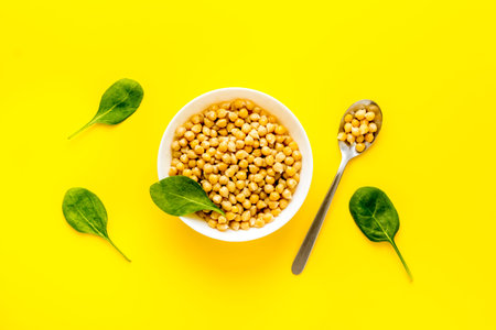 Raw chickpeas in bowl on yellow kitchen table top view