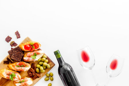 Wine appetizer. Toasts, nuts, olives on white desk top view copy space