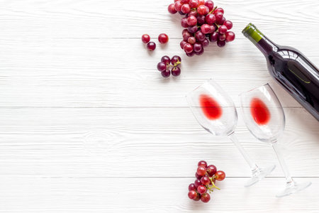 Red wine with grape - in glasses and bottle - on white desk top view copy space
