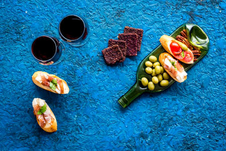 Toasts with prosciutto and tomatoes on glass bottle plate with red wine top viewの写真素材