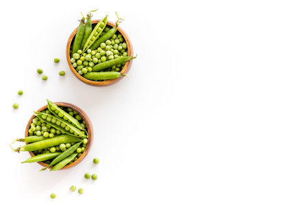 Set of green pea pods in wooden bowl on kitchen table desk