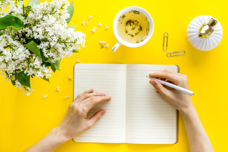 Woman s hands writing on office table desk with flowers. Education concept