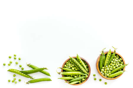 Set of green pea pods in wooden bowl on kitchen table deskの写真素材