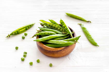 Green pea pods in wooden bowl on the kitchen backgroundの写真素材