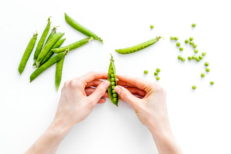 Sweet green peas in hands. Top view on kitchen table desk