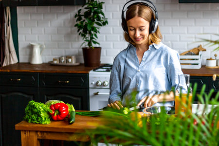 Cooking woman in the kitchen in the headphones with colorfull vegetables