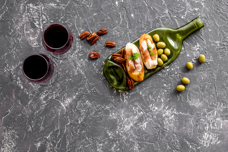 Antipasto on glass bottle plate and red wine in glasses top-down copy space