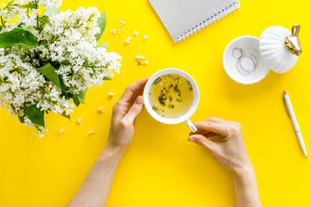 Cup tea with girl s hands and jasmine flowers bouquet. Bright table top viewの写真素材