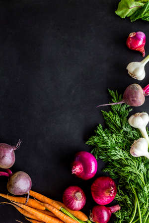 Flat lay of fresh vegetables and greenery on black table top-down copy spaceの写真素材