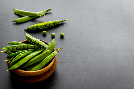Set of green pea pods in wooden bowl on kitchen table deskの写真素材