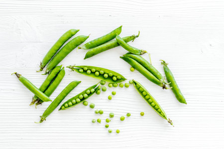 Top view of green pea pods and peas on the kitchen background