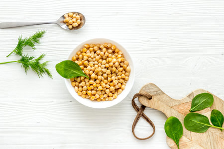 Raw chickpeas in bowl on white kitchen table top view