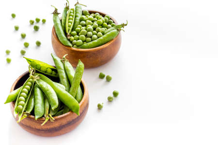 Set of green pea pods in wooden bowl on kitchen table deskの写真素材