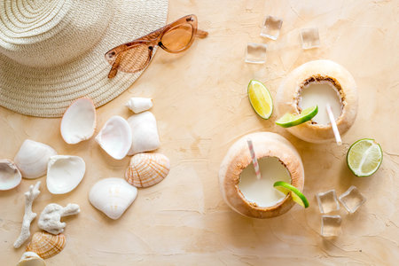 Tropical coconut drink with straw on beach background, top view