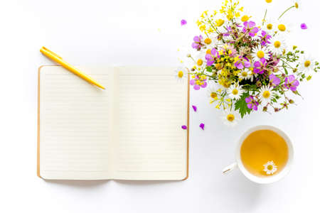 Bouquet of wild summer flowers with tea and open notepad. Above viewの写真素材