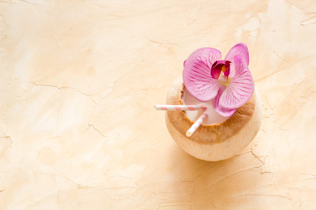 Fresh coconut with straw tropical drink and orchid flower, top view copy space