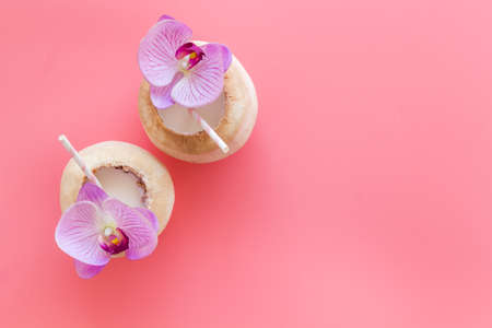 Raw coconut water or milk with straw and orchid flower, above viewの写真素材