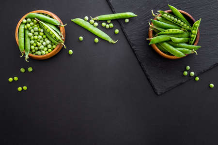 Green pea pods in wooden bowl on the kitchen backgroundの写真素材