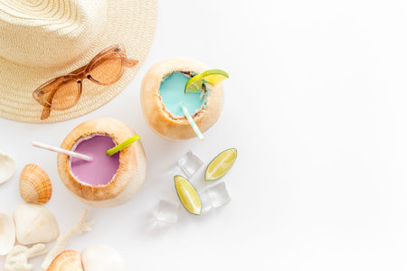 Young coconut water with straw on beach background, top view