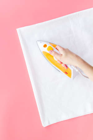 Female hand with iron - ironing clothes. Top view, copy spaceの写真素材
