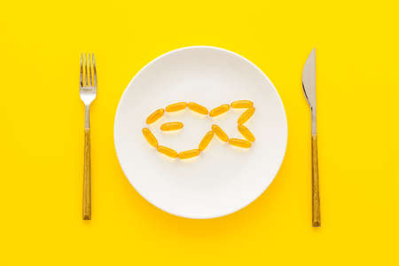 Omega cod liver oil capsules on plate with fish shape, top viewの写真素材