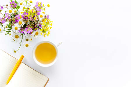 Wild flowers bouquet with cup tea on a table, top view