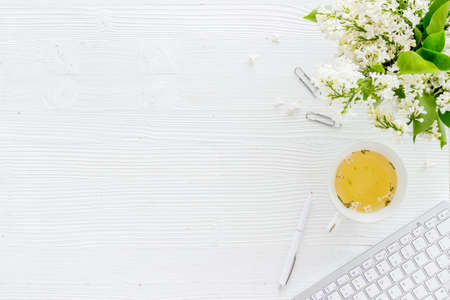 Top view of jasmine flowers bouquet with notebook and cup tea on working place