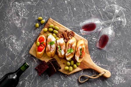 Antipasto on cutting board and red wine in bottle top-downの写真素材