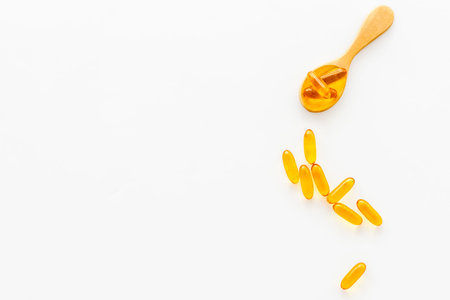 Omega cod liver oil capsules in wooden spoon, top view