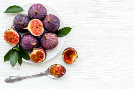Fresh whole and sliced figs on a plate with green leaves. Top viewの写真素材