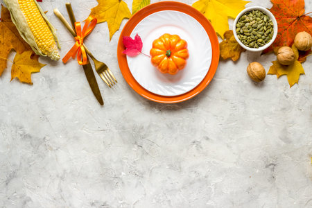 Thanksgiving concept with place setting pumpkins and leaves on a dinner table