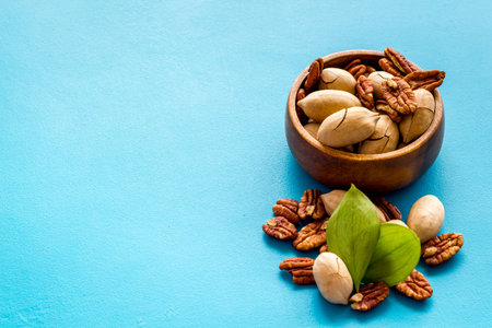 Pecan nuts with leaves in bowl on the table, close up