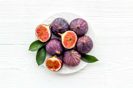 Fresh figs in on a plate with green leaves. Top viewの写真素材