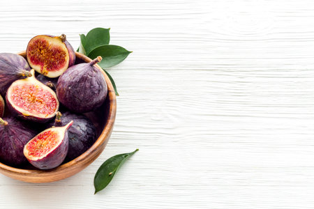 Fresh figs in a bowl with green leaves. Top view