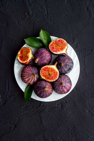 Fresh figs in on a plate with green leaves. Top viewの写真素材