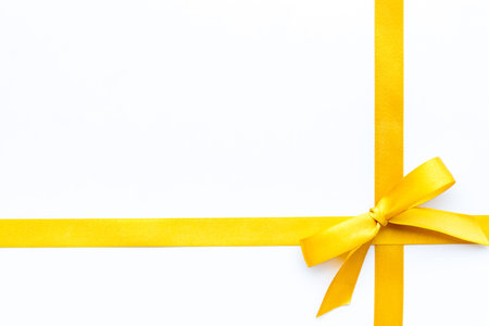 Yellow ribbon with bow isolated. Top view, copy space