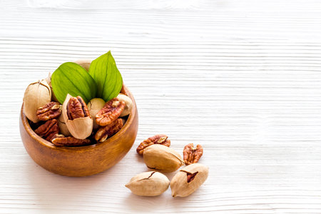Pecan nuts with leaves in bowl on the table, close up