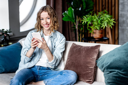 Blond smiling girl using smartphone at home