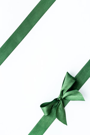 Festive green ribbon with bow isolated on white. Top view, copy spaceの写真素材