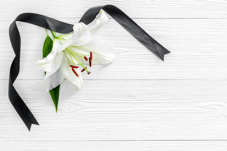Flat lay of lily flowers and black ribbon. Funeral symbolの写真素材