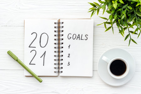 Inspiration concept - New Years goals written in notebook on a table, flat lay