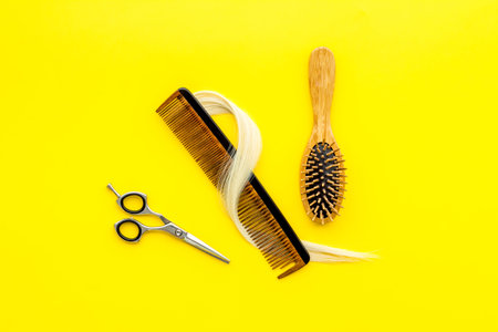 Hairdresser scissors with lock of blond hair and comb, top view