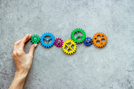 Teamwork concept. Hand connecting gears into puzzle - symbol of working mechanismの写真素材