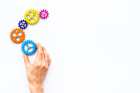 Teamwork concept. Hand connecting gears into puzzle - symbol of working mechanismの写真素材