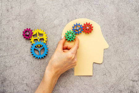 Brain of gears. Hand put peace of puzzles on paper head. Mental works conceptの写真素材