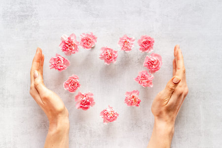 Heart shape of flowers with hands. Valentines Day, wedding or birthday greeting card, top viewの写真素材