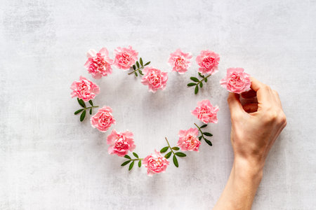 Heart shape of flowers with hands. Valentines Day, wedding or birthday greeting card, top view