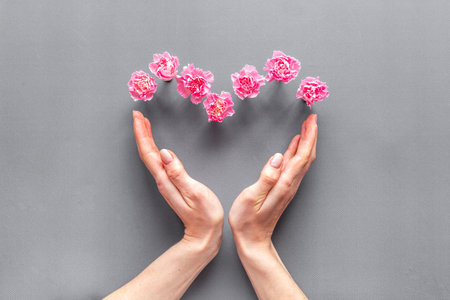 Heart shape of flowers with hands. Valentines Day, wedding or birthday greeting card, top viewの写真素材