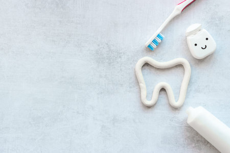 Tooth shape with tube of toothpaste and toothbrush. Dental hygiene concept, top view
