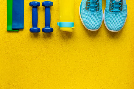Top view of fitness accessories with dumbbells and sneakers